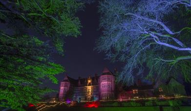 The front of Knightshayes Court in Tiverton lit up at night